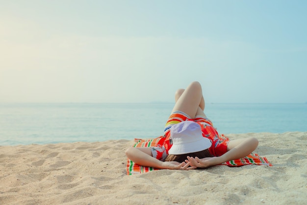 Gelukkige reizigersvrouw in rode jurk geniet van haar tropische strandvakantie