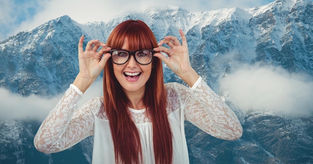 Foto gelukkige roodharige vrouw die een bril draagt tegen besneeuwde bergen