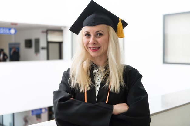 Foto gelukkige schattige blonde blanke afgestudeerde meisje glimlacht - ze is in een zwart mortel bord