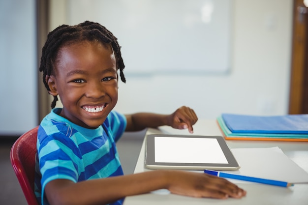Gelukkige schooljongen met digitale tablet in klaslokaal