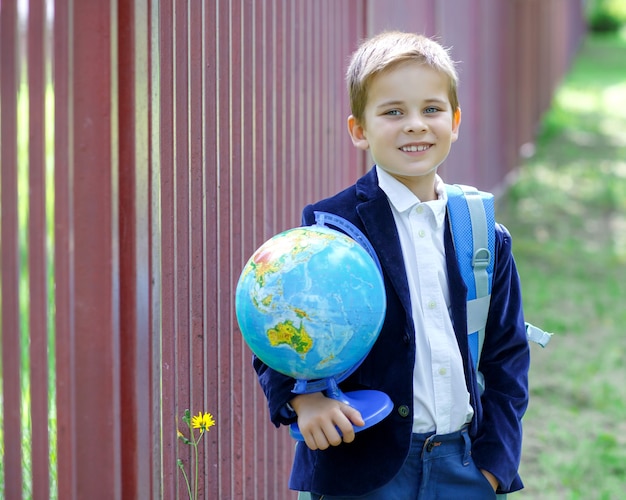 Gelukkige schooljongen met wereldbol eerste keer naar school