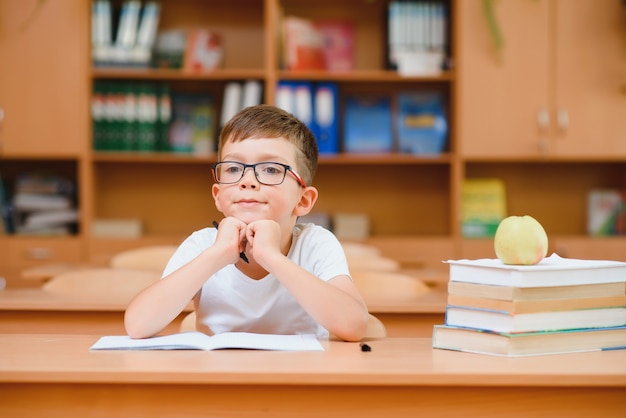 Gelukkige schooljongens zitten aan bureau, klaslokaal