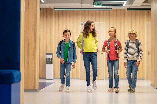 Gelukkige schoolkinderen lopen pratend in de gang