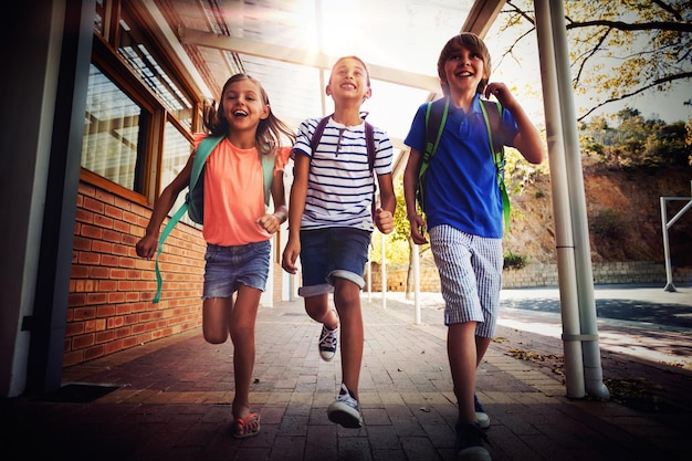 Foto gelukkige schoolkinderen rennen in de gang op school