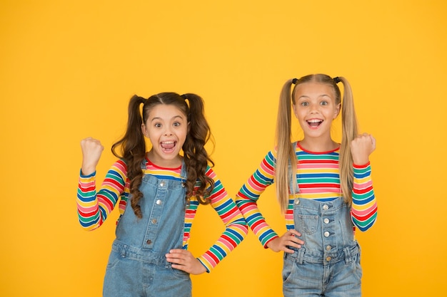 Gelukkige schoolkinderen vriendschap. beste vrienden voor altijd. kleine zusjes veel plezier. kleine meisjes gele achtergrond. kapsalon. zomermode voor kinderen. schoonheid en stijl. jeugd geluk.