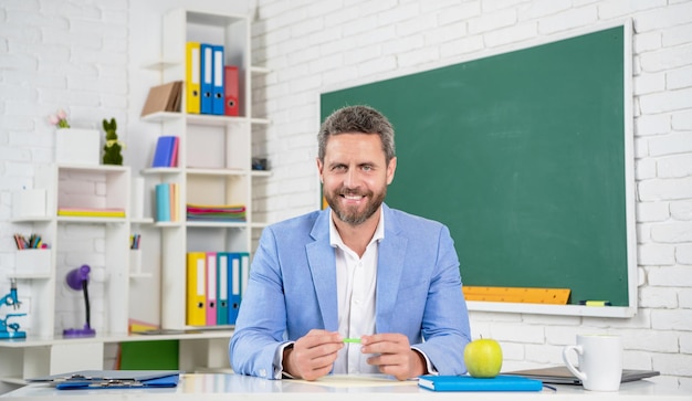 Foto gelukkige schoolleraar in klaslokaal bij bord