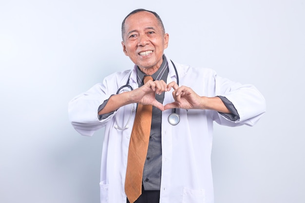 Gelukkige senior Aziatische arts man die een hartvormig symbool maakt met vingers