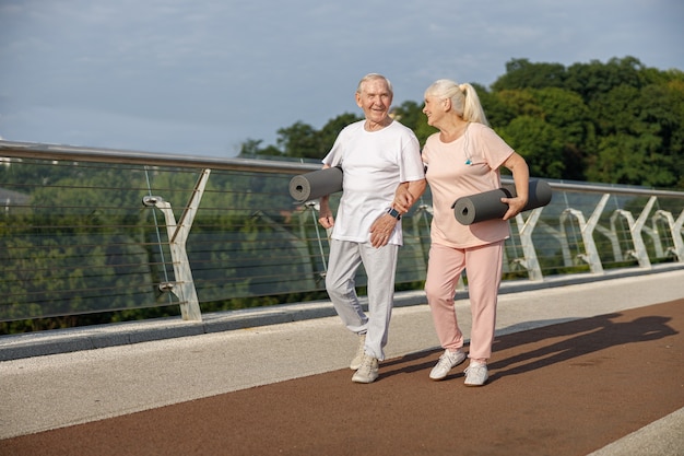 Gelukkige senior man en dame klaar voor training lopen langs voetgangersbrug