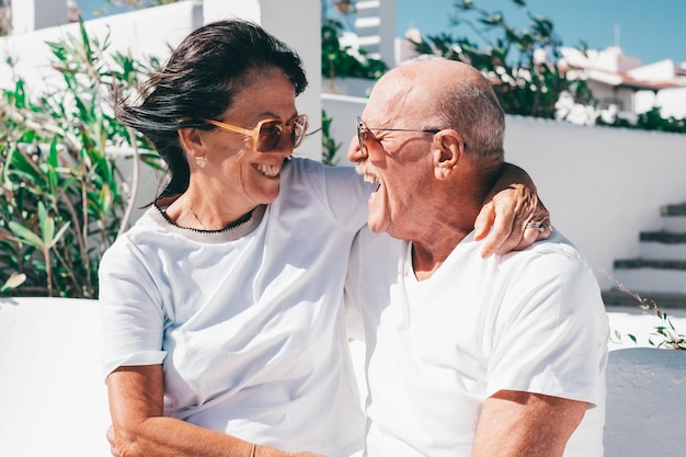 Gelukkige senior paar zittend in een bankje lachend knuffelen met liefde kijkend in elkaars ogen