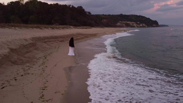 Gelukkige sensuele jonge vrouw die 's avonds op het strand rent