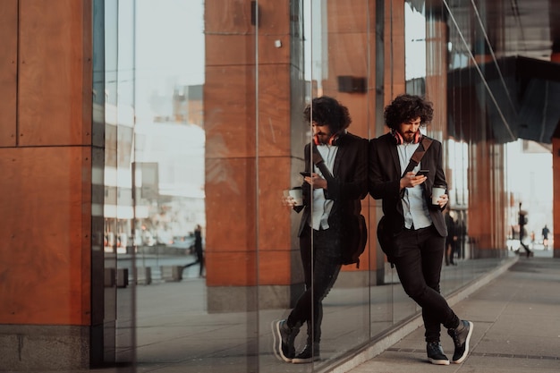 Gelukkige student met afro-kapsel die op de campus loopt terwijl hij zijn mantas en zijn koptelefoon draagt.