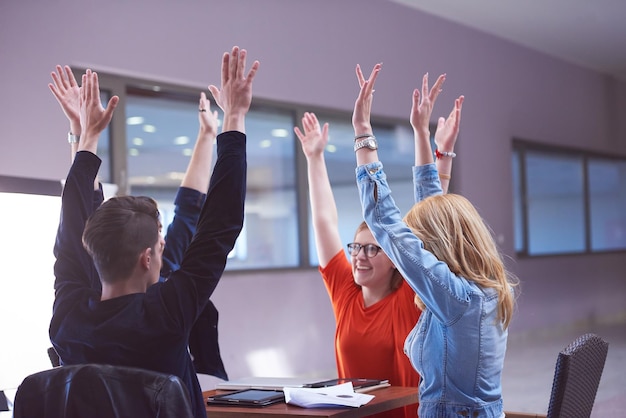 Foto gelukkige studenten vieren vrienden groep samen op school jonge mensen steken handen stapelen en krijgen in cirkelformatie samen