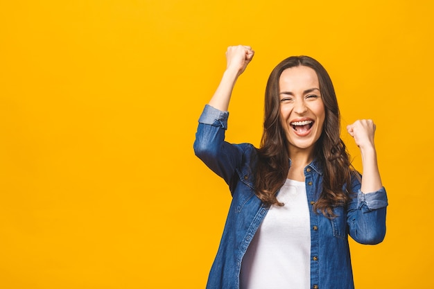 Gelukkige succesvolle jonge vrouw met opgeheven handen die en succes schreeuwen vieren