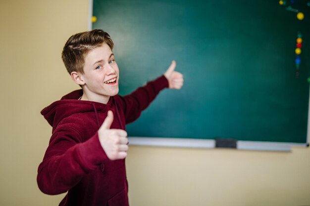 Gelukkige tiener in vrijetijdskleding bij het schoolbord School en onderwijsconcept