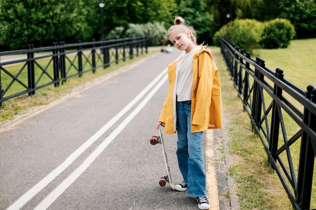 Foto gelukkige tienermeisje leert skateboarden in het stadspark.