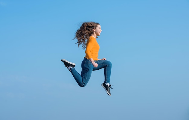 Gelukkige tienermeisje springt hoog op de lucht achtergrond vitaliteit