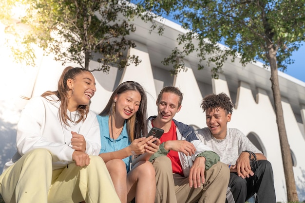 Gelukkige tienervrienden die naar de mobiele telefoon kijken en lachen in de technologie voor jongeren op straat in de stad