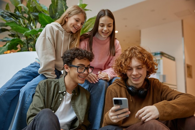 Foto gelukkige tienervrienden kijken naar grappige video's op hun smartphone in het winkelcentrum.