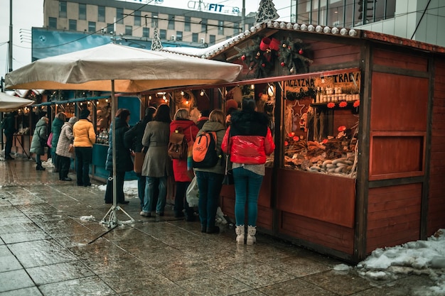 Gelukkige toeristen staan op een kerstmarkt in Polen verlichte versieringen tijdens de winter