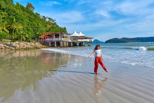 Gelukkige toeristenvrouw geniet van reizen op het centrale strand van het tropische eiland Langkawi
