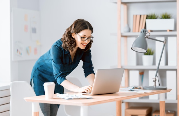 Gelukkige toevallige mooie vrouw die aan laptop thuis werkt.