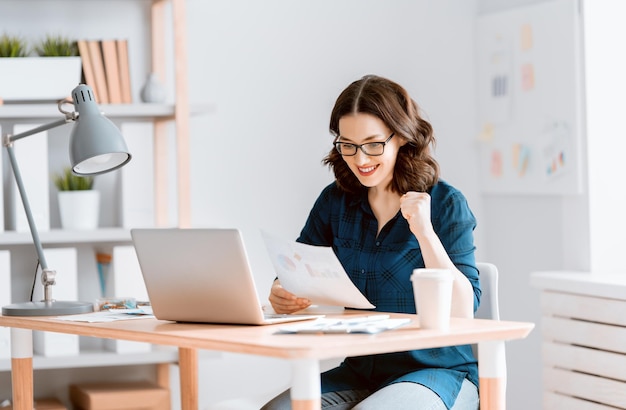 Gelukkige toevallige mooie vrouw die aan laptop thuis werkt.