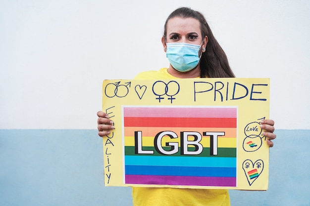 Gelukkige transgendervrouw die met masker lgbt-banner houdt bij vrolijke parade