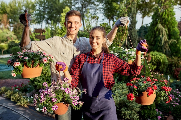 Gelukkige tuinmannen voor jongens en meisjes houden op een zonnige dag potten met petunia in de prachtige tuin. .