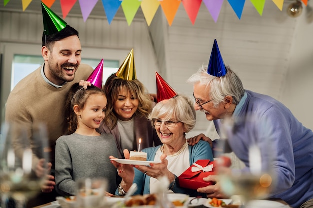 Gelukkige uitgebreide familie die plezier heeft tijdens het verjaardagsfeestje van de senior vrouw in de eetkamer