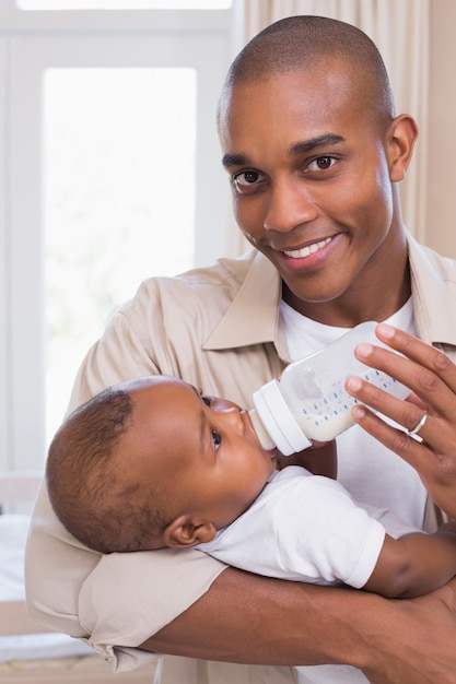 Gelukkige vader die zijn babyjongen een fles voedt