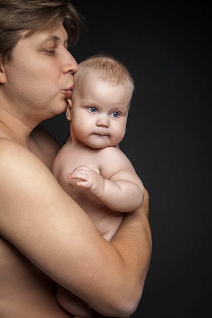 Gelukkige vader die zijn pasgeboren baby knuffelt en kust