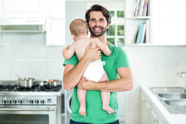 Gelukkige vader dragende zoon in keuken