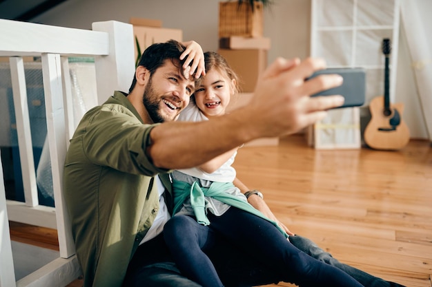 Gelukkige vader en dochter nemen selfie in hun nieuwe appartement