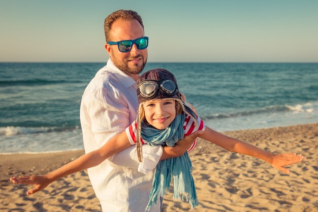 Foto gelukkige vader en dochter spelen en plezier hebben op zomervakantie op het strand