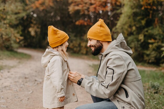 Gelukkige vader en dochter spelen tijdens het wandelen in een prachtig herfstpark Ideale weekendvader met zijn dochtertje herfststemming