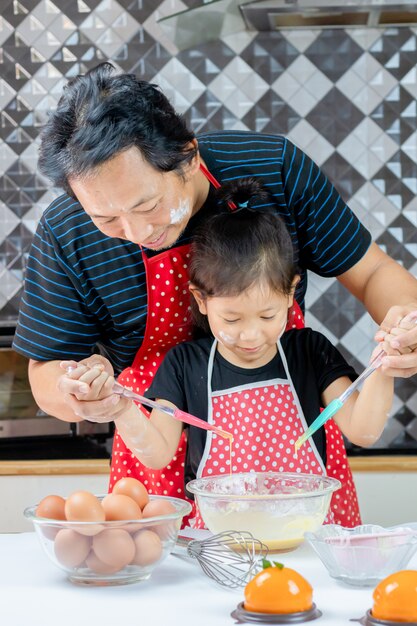 Foto gelukkige vader en kleine dochter koken in de keuken