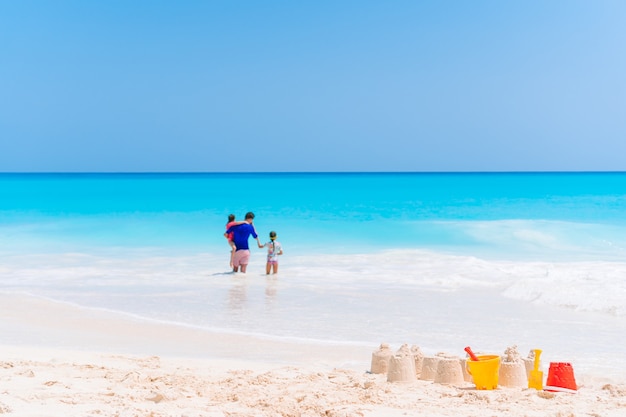 Gelukkige vader en schattige kleine kinderen op tropisch strand met plezier. Familie vakantie