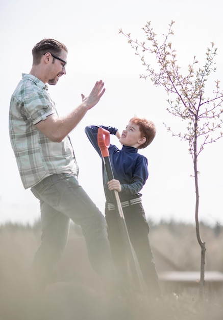 Gelukkige vader en zoon die een boom planten