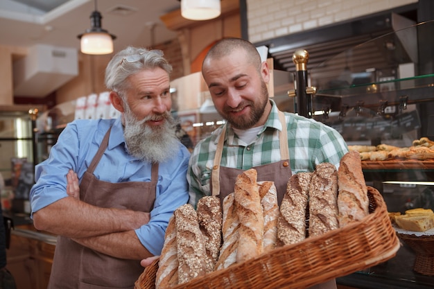 Foto gelukkige vader en zoon die heerlijk vers gebakken brood verkopen bij hun familiebakkerij