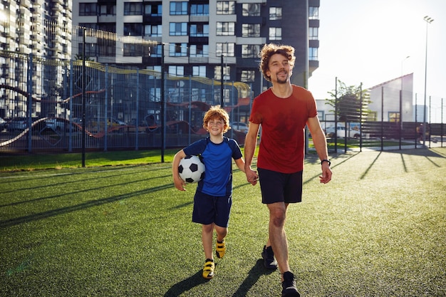 Gelukkige vader en zoon kind lopen op het voetbalveld