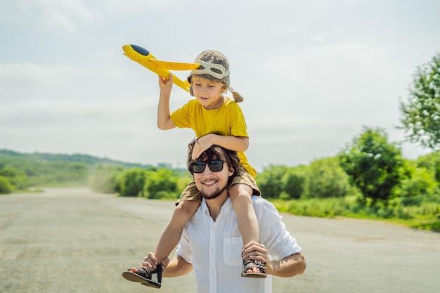 Gelukkige vader en zoon spelen met speelgoedvliegtuig tegen de achtergrond van de oude landingsbaan Reizen met kinderen concept