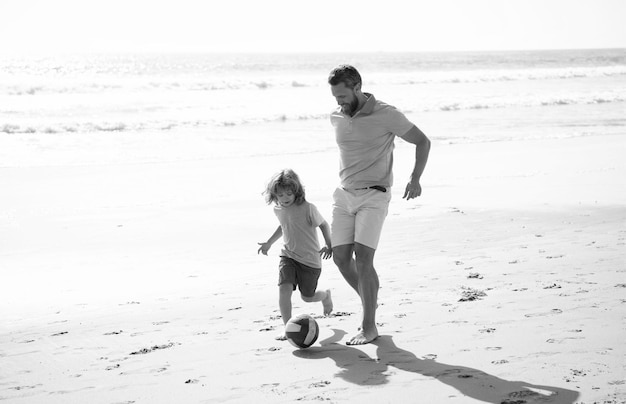 Gelukkige vader en zoon voetballen met plezier op zomer zandstrand familie vakantie voetbal