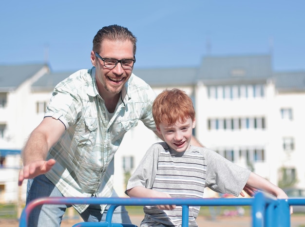 Gelukkige vader en zoontje op de speelplaatshet concept van ouderschap