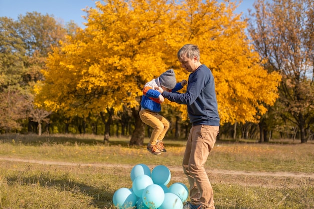 Gelukkige vader geniet van de vrije dag met zijn kind in het herfstpark Spelen met ballonnen