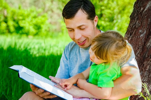 Gelukkige vader met een kind dat een boek leest over de aard van de Bijbel