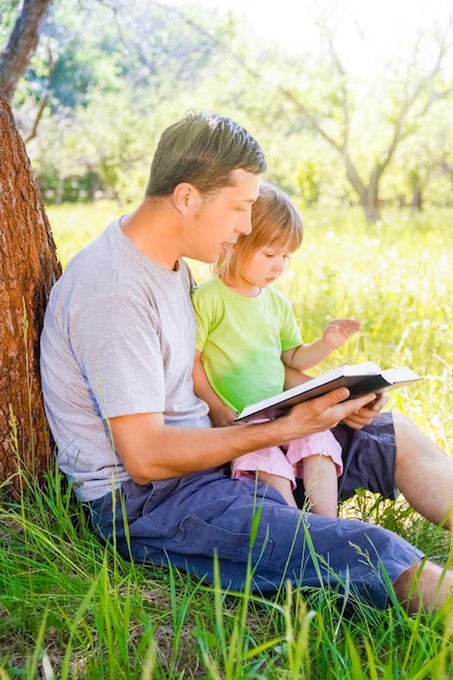 Gelukkige vader met een kind dat een boek leest over de aard van de Bijbel