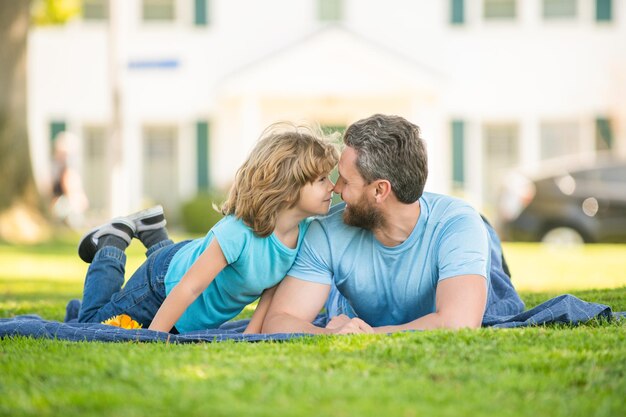 Gelukkige vader met zoon ontspannen samen op groen parkgras vaderschap