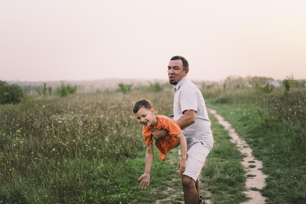 Gelukkige Vaderdag Vader met zoon lopen in het veld Vader knuffelt jongen Het concept van vaderdagrelaties met zorg en liefde voor kinderen