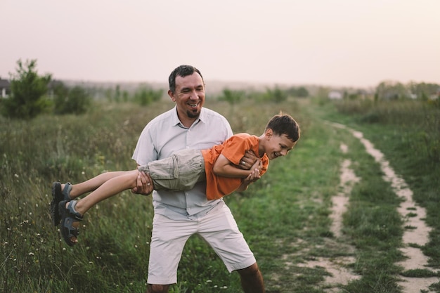 Gelukkige Vaderdag Vader met zoon lopen in het veld Vader knuffelt jongen Het concept van vaderdagrelaties met zorg en liefde voor kinderen