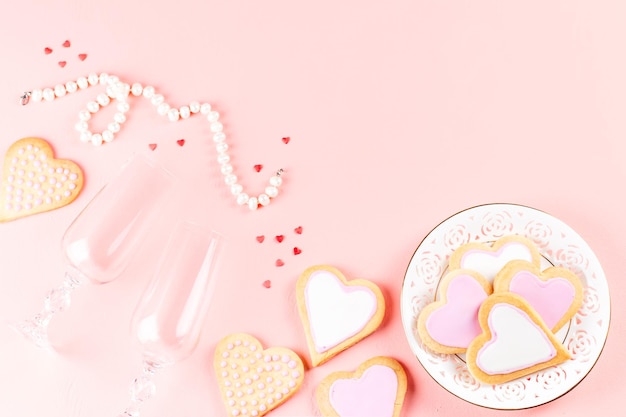 Foto gelukkige valentijnsdag kaartje met hart koekjes wijn glazen en wijn op pastel roze achtergrond